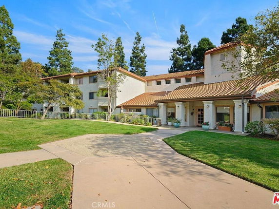 Front view of a multi-story building with tiled roofs and a landscaped entrance.