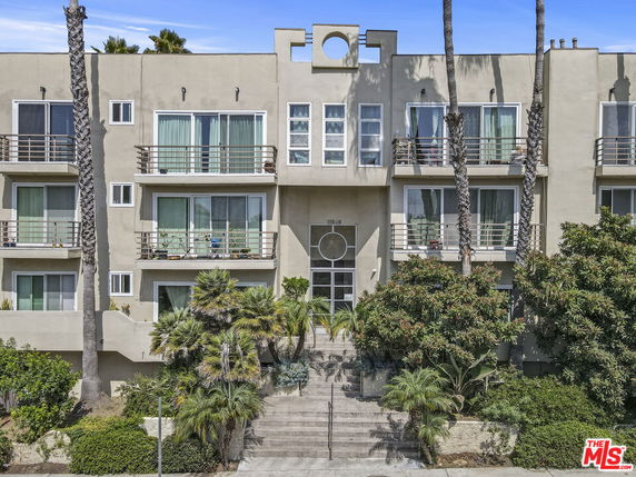 Front view of a multi-story building with balconies and a central entrance.