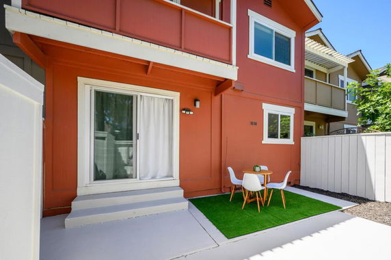 Front view of a two-story house with red exterior and patio area.