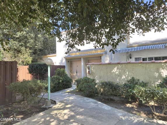 Front view of a two-story house with a walkway and surrounding greenery.