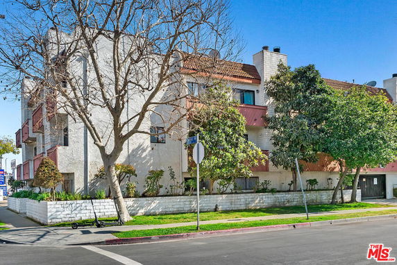 Front view of a multi-story residential building with balconies and a red-tiled roof.