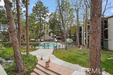 Outdoor area with a swimming pool surrounded by trees and buildings.