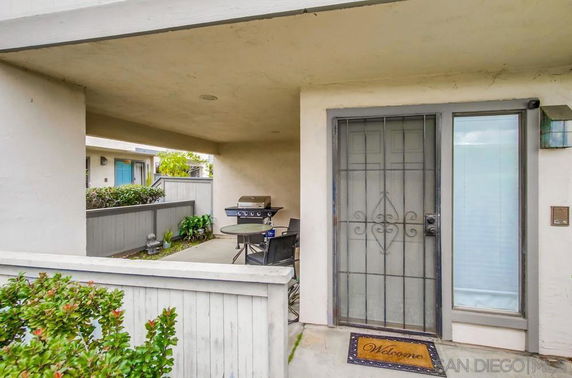 Front view of a house entrance with a metal door and a small patio area.