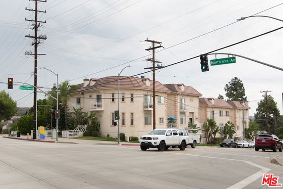 Front view of a multi-story residential building on a street corner.