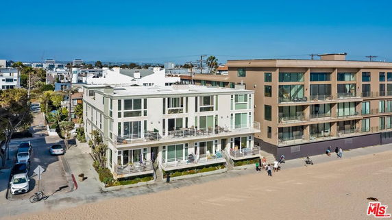 Front view of a multi-story beachfront building with large windows and balconies.