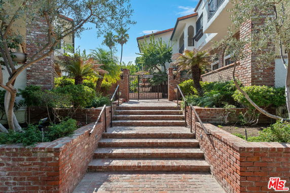 Front view of a building with brick steps and a gated entrance.