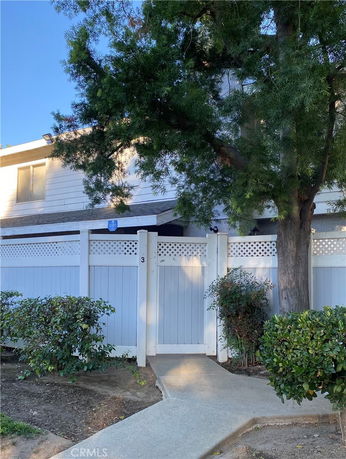 Front view of a house with a white fence and greenery.