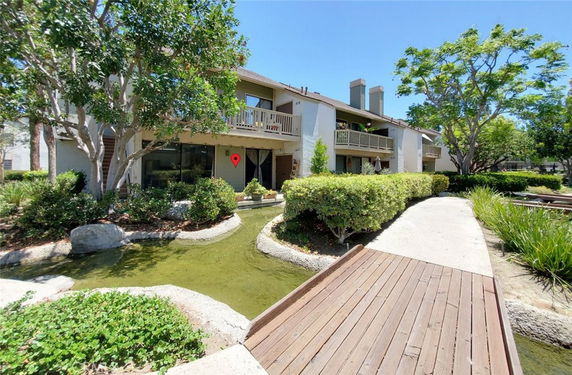Front view of a two-story residential building with balconies and landscaped surroundings.