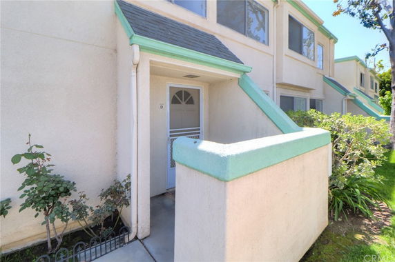 Front view of a multi-story building with a small porch area and entrance door.