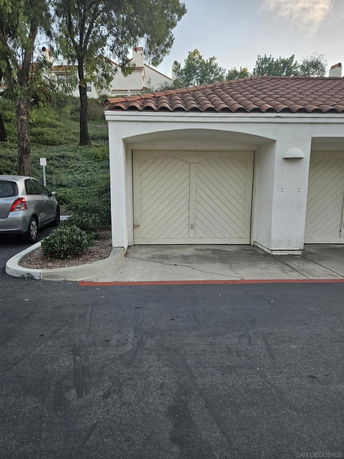Outdoor parking area with a covered garage and a parked car.