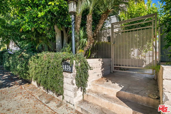 Entrance view of a house with a metal gate and stone stairs.