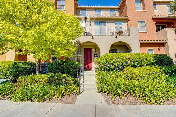 Front view of a multi-story house with a red door and arched entryways.