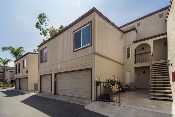 Front view of a two-story residential building with garages and an exterior staircase.