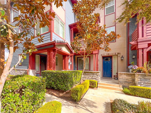 Front view of a multi-story house with colorful facade and landscaped entrance.