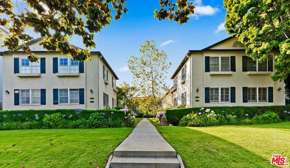 Front view of two adjacent two-story houses with shutters on windows.
