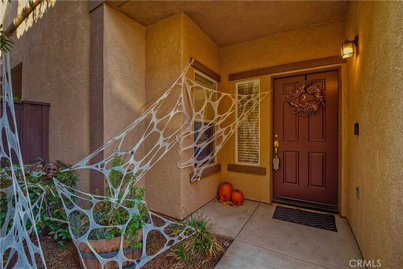 Front view of a house entrance decorated with spider webs and pumpkins.