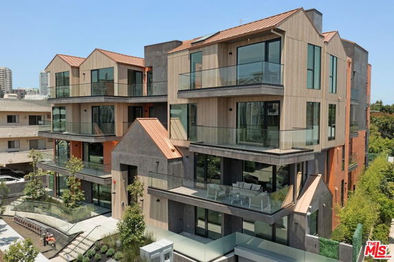 Front view of a modern multi-story building with large glass windows and balconies.