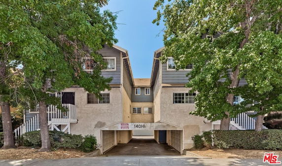 Front view of a multi-story building with driveway and trees.