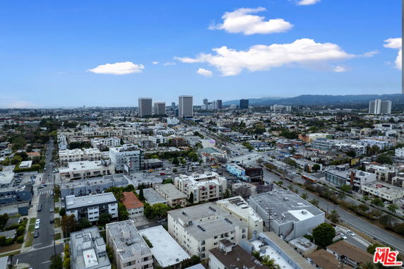 Wide-angle aerial view of a cityscape with various buildings and distant mountains.