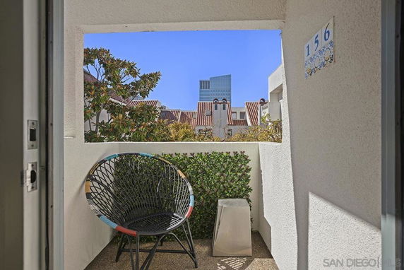 View from a balcony with a chair overlooking neighboring buildings and trees.