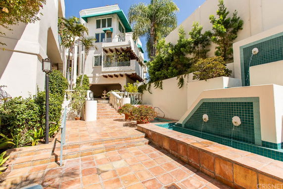 Front view of a multiple-story building with balconies and landscaped entrance.