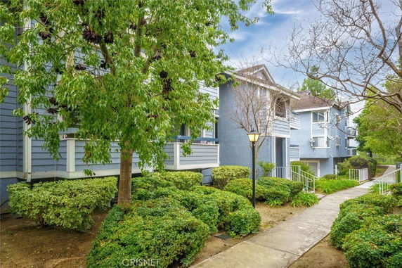 Front view of a multi-unit residential building with a pathway and greenery.