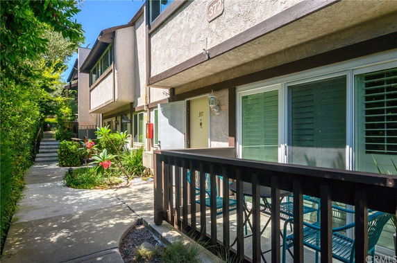 Front view of a multi-story residential building with a small patio area.