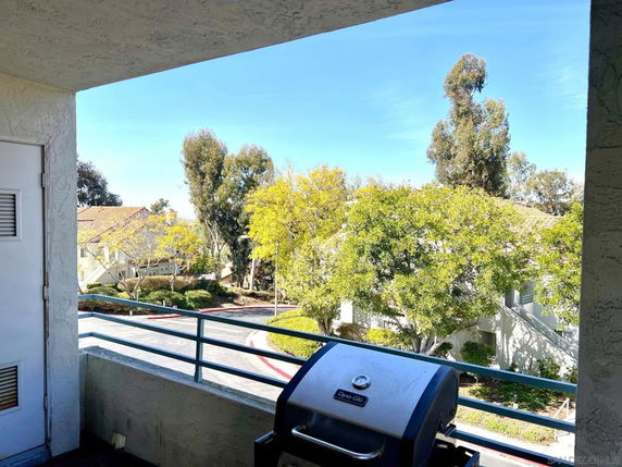 View from a balcony displaying trees and nearby buildings.