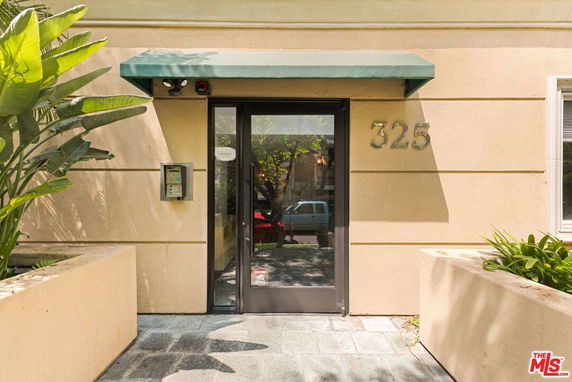 Front view of a building entrance with a green awning and glass door, marked with the number 325.