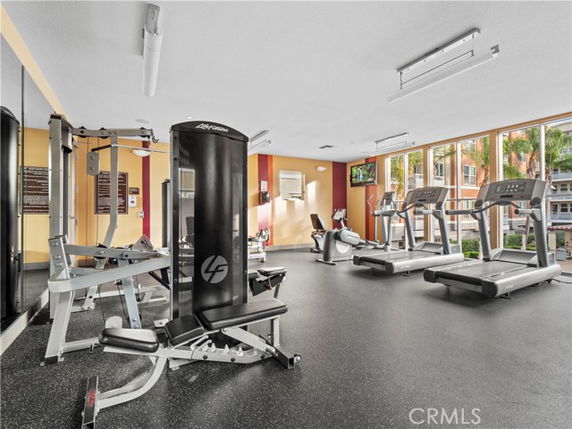 Indoor gym area with exercise equipment and large windows.