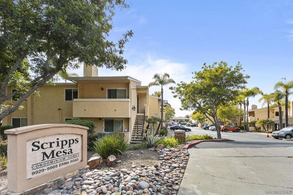 Front view of a multi-story condominium building with exterior stairs.