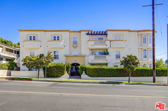 Front view of a multi-story residential building with balconies and a central entrance.