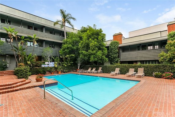 Outdoor view with an apartment complex surrounding a swimming pool.