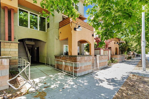 Front view of a multi-story building with a stairway and archway entrance.