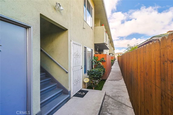 Side view of an apartment building with stairs and a narrow pathway.