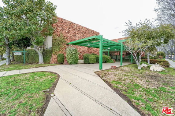 Front view of a building with stone facade and green pergola.