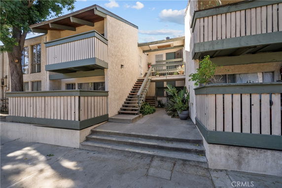 Front view of an apartment building with stairs leading to the entrance.
