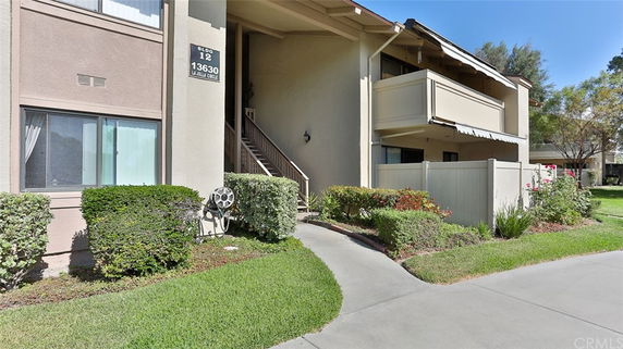 Front view of a two-story residential building with balconies and an entrance stairway.