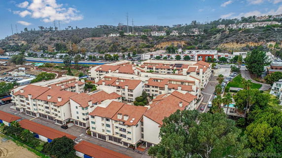 Aerial view of a complex with multiple buildings featuring red roofs and a hilly landscape in the background.