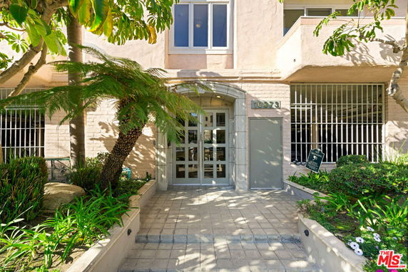 Front view of a building entrance with plants and a pathway.