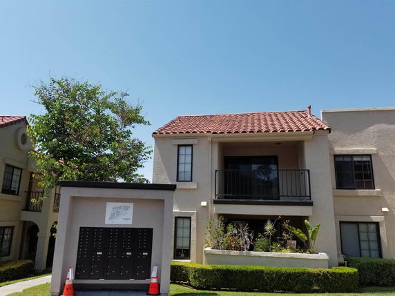 Front view of a two-story building with a balcony and red tile roof.