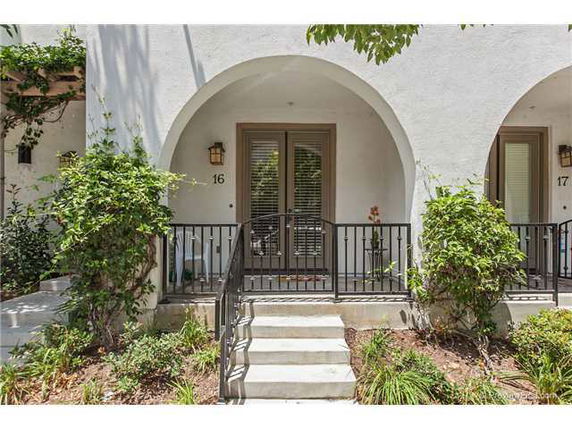 Front view of a house with an arched entrance and stairway leading to the door.