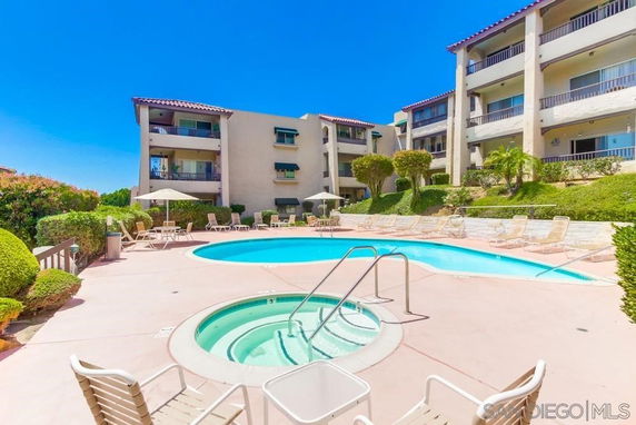 Outdoor view of a residential complex with a swimming pool and surrounding lounge chairs.