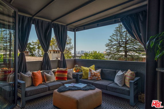 Rooftop terrace with seating and a view of surrounding trees and cityscape.