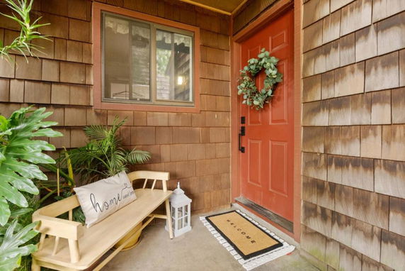 Front view of a house with a red door and wood shingle siding.