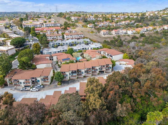 Aerial view of a residential area with multiple houses, surrounded by trees and open land.
