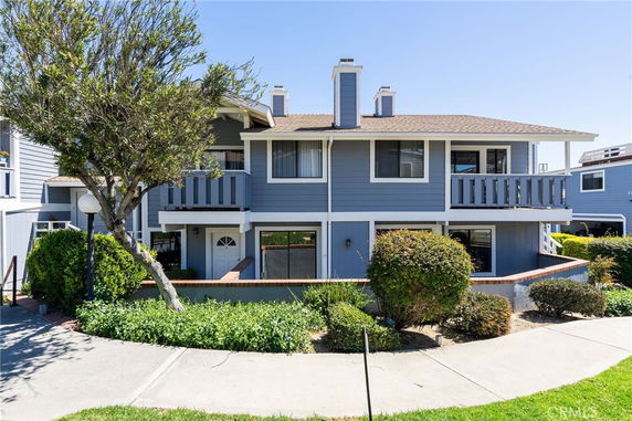 Front view of a two-story house with a wooden exterior and balconies.