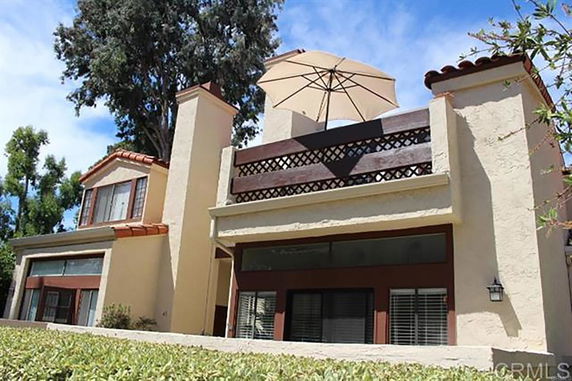 Front view of a house with a balcony featuring an umbrella.