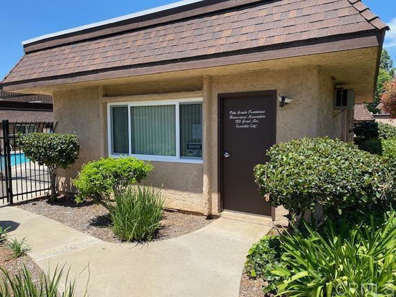 Front view of a small building with a brown door and window beside it.