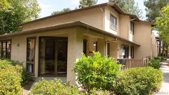 Front view of a two-story residential building with beige exterior and large windows.